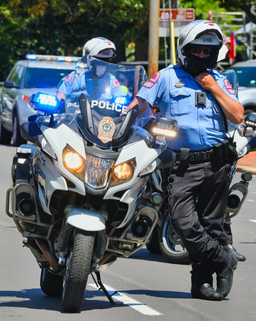 policeman in a blue shirt and white helmet standing next to his white motorcycle