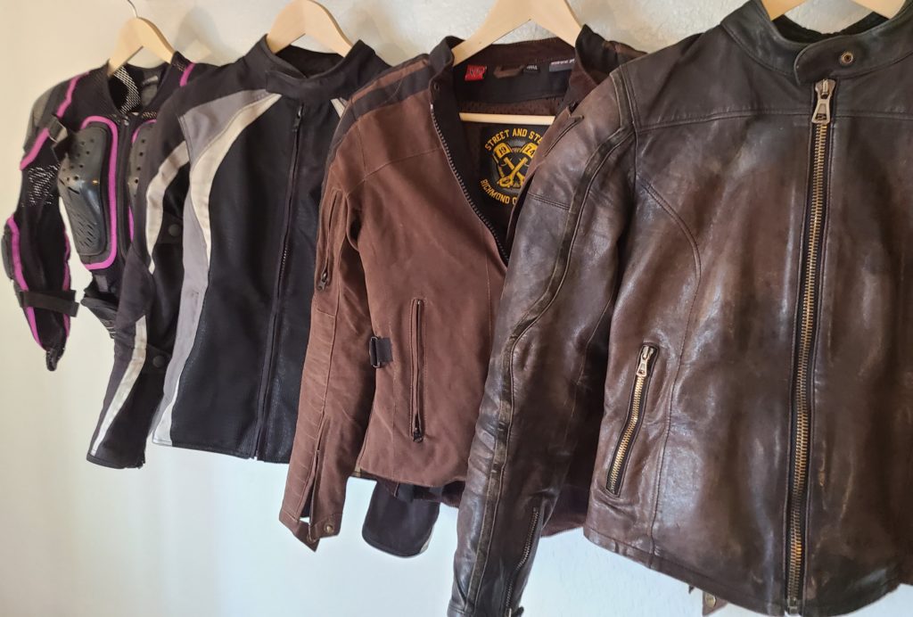 4 motorcycle jackets - 2 brown and 2 black - hanging in a row